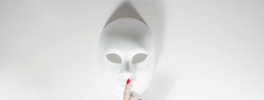 Eine weiße Maske mit einem Finger davor