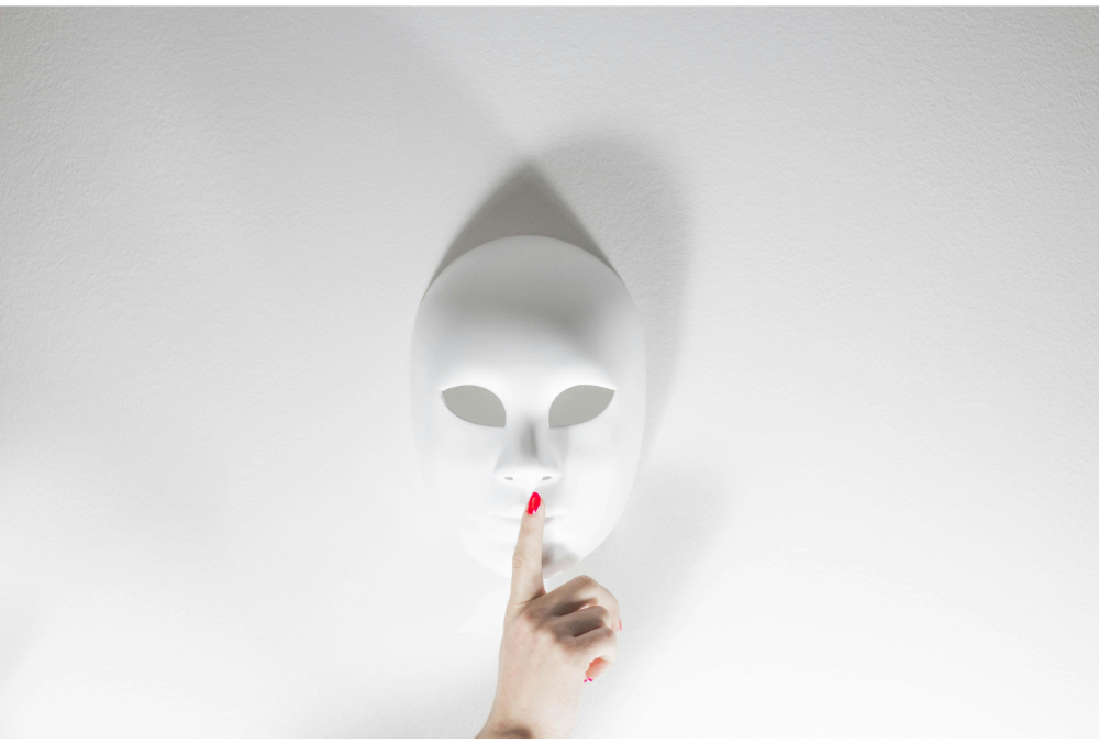 Eine weiße Maske mit einem Finger davor